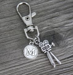 a metal keychain with the letter m on it and two keys attached to it