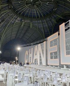 rows of white chairs in front of a chandelier with the word chandel written on it