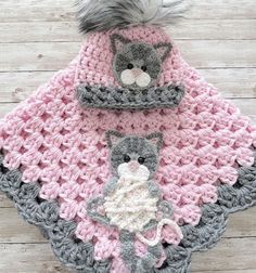 a crocheted blanket with two cats and a cat hat on top of it