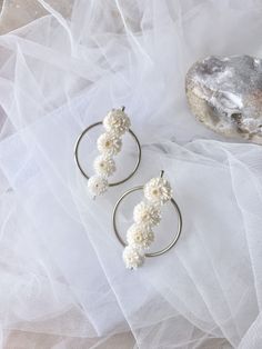 two rings with flowers on them sitting on a white cloth next to a piece of rock