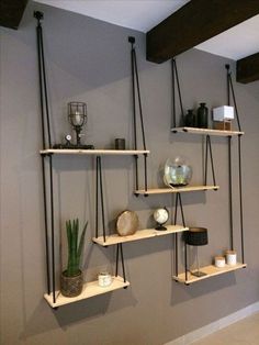 three shelves with plants, candles and other items on them against a wall in a living room