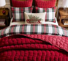 a bed with red and white plaid comforter, pillows and christmas decorations on it