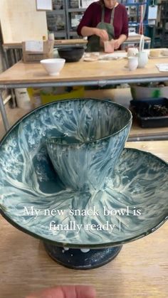 a glass bowl sitting on top of a wooden table next to a person in the background