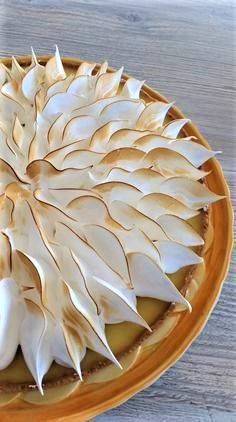 a pie with white frosting on top sitting on a table