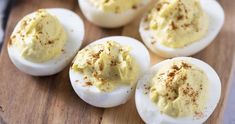 deviled eggs on a wooden cutting board with seasoning