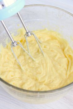 a bowl filled with yellow batter and two beaters