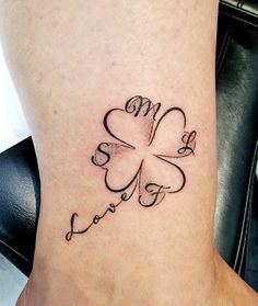 a four leaf clover tattoo with the word love written in cursive writing on it