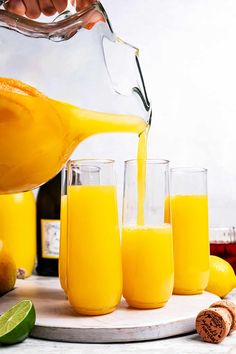 a pitcher pouring orange juice into glasses