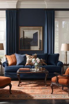 a living room with blue couches and orange chairs in front of two windows that have curtains on them