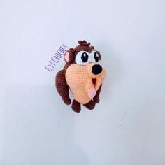 a crocheted stuffed animal hanging on the wall with its mouth open and tongue out