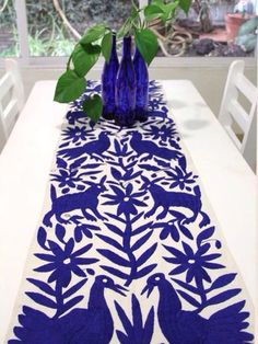 a table with blue vases sitting on top of it next to a white table cloth