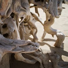 some very old looking wood pieces on the sand and dirt ground with no one around them