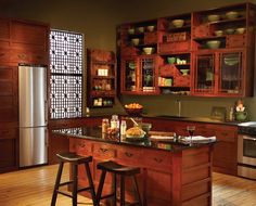 a kitchen with wooden cabinets and black counter tops, two stools in front of the island