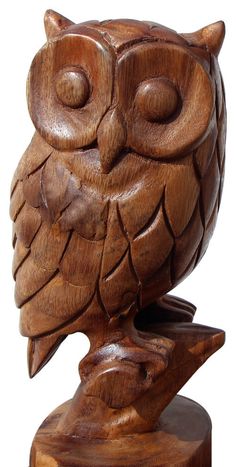 an owl carved from wood sitting on top of a wooden stand