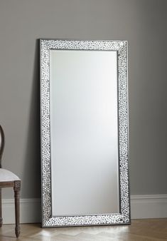 a mirror sitting on top of a wooden floor next to a chair