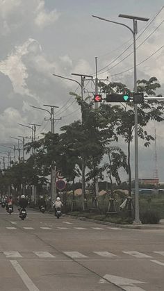 people are riding motorcycles down the street at an intersection with traffic lights and power lines