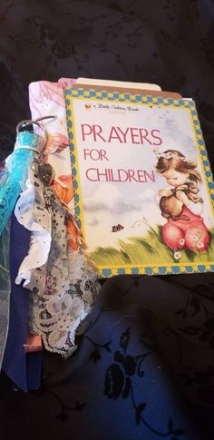 an open book on a table next to some lace and ribbon wrapped around it with the words prayers for children