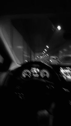 black and white photograph of the inside of a car with dashboard lights on at night