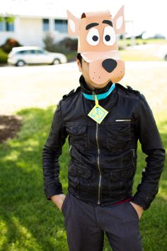 a man standing in the grass wearing a paper dog mask