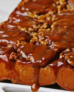 a bundt cake covered in caramel sauce and walnuts on a white plate