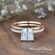 an engagement ring with a princess cut diamond in the center and side stones on each band