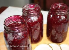 three jars filled with jelly sitting on top of a wooden cutting board