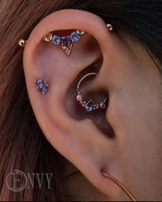 a woman wearing ear piercings with blue and clear stones on the side of her ear