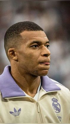 a close up of a person wearing a jacket and looking off into the distance with a crowd in the background