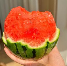 a person holding a watermelon slice in their hand