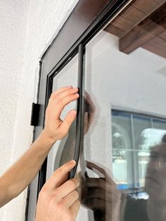 a person holding onto the side of a window with their hand on the glass door