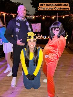 three people dressed in costumes posing for a photo at an outdoor event with lights on the background