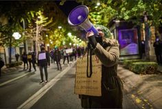 a person holding a megaphone up to their face while walking down the street at night