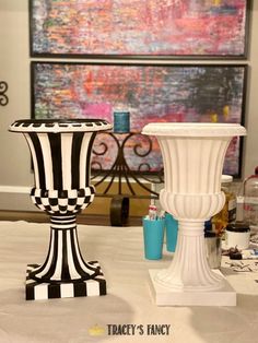 two black and white vases sitting on top of a table