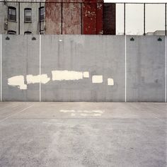 an empty parking lot in front of a building with graffiti on the wall and windows