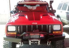 the front end of a red jeep parked in a parking lot