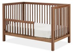 a wooden crib with white sheets in it