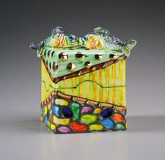 a ceramic box with two fish on it's sides and colorful glass beads around the edges