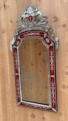 a red and silver mirror hanging on a wooden wall