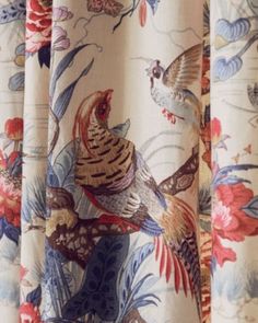 the curtain is decorated with colorful birds and flowers on it's side, while another bird flies in the background