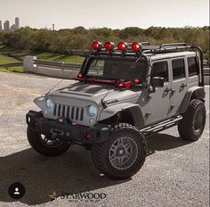 a gray jeep with red lights on it's roof is parked in the parking lot