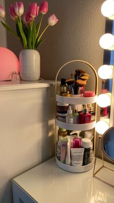 a white vanity with pink tulips in the corner and a mirror behind it