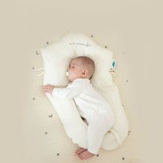 a baby is sleeping on a pillow in the shape of a moon with stars around it