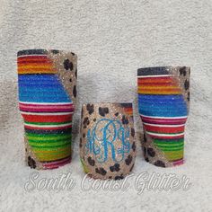 three personalized tumblers with colorful stripes and leopard print on them, one has a monogrammed initial