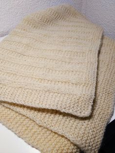 two knitted blankets sitting on top of a white table