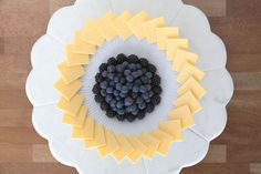 a plate topped with cheese and berries on top of a wooden table