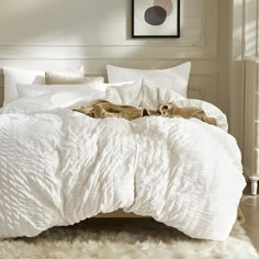 an unmade bed with white comforter and pillows on it in a bedroom setting