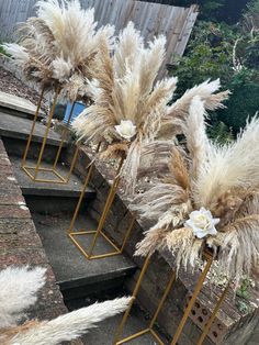 three metal planters with flowers and grass in them on the side of some steps