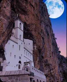 an old church built into the side of a mountain with a full moon in the background