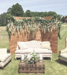 an outdoor seating area with couches, chairs and a wooden wall covered in vines