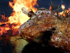 a piece of meat sitting on top of a table next to a fire